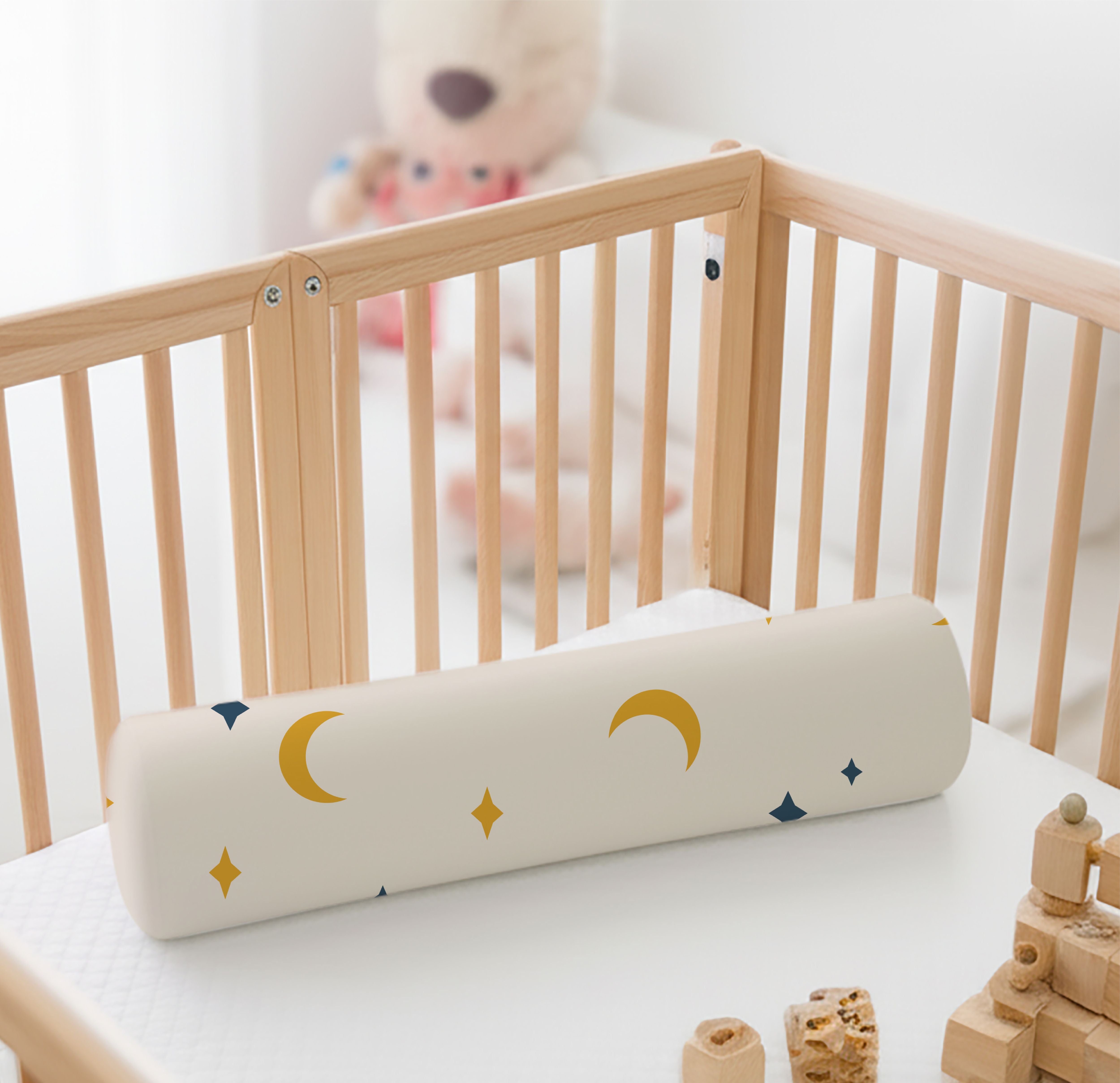 ADMIRAE baby bolster pillow with moon and star patterns placed in a wooden crib for infant comfort