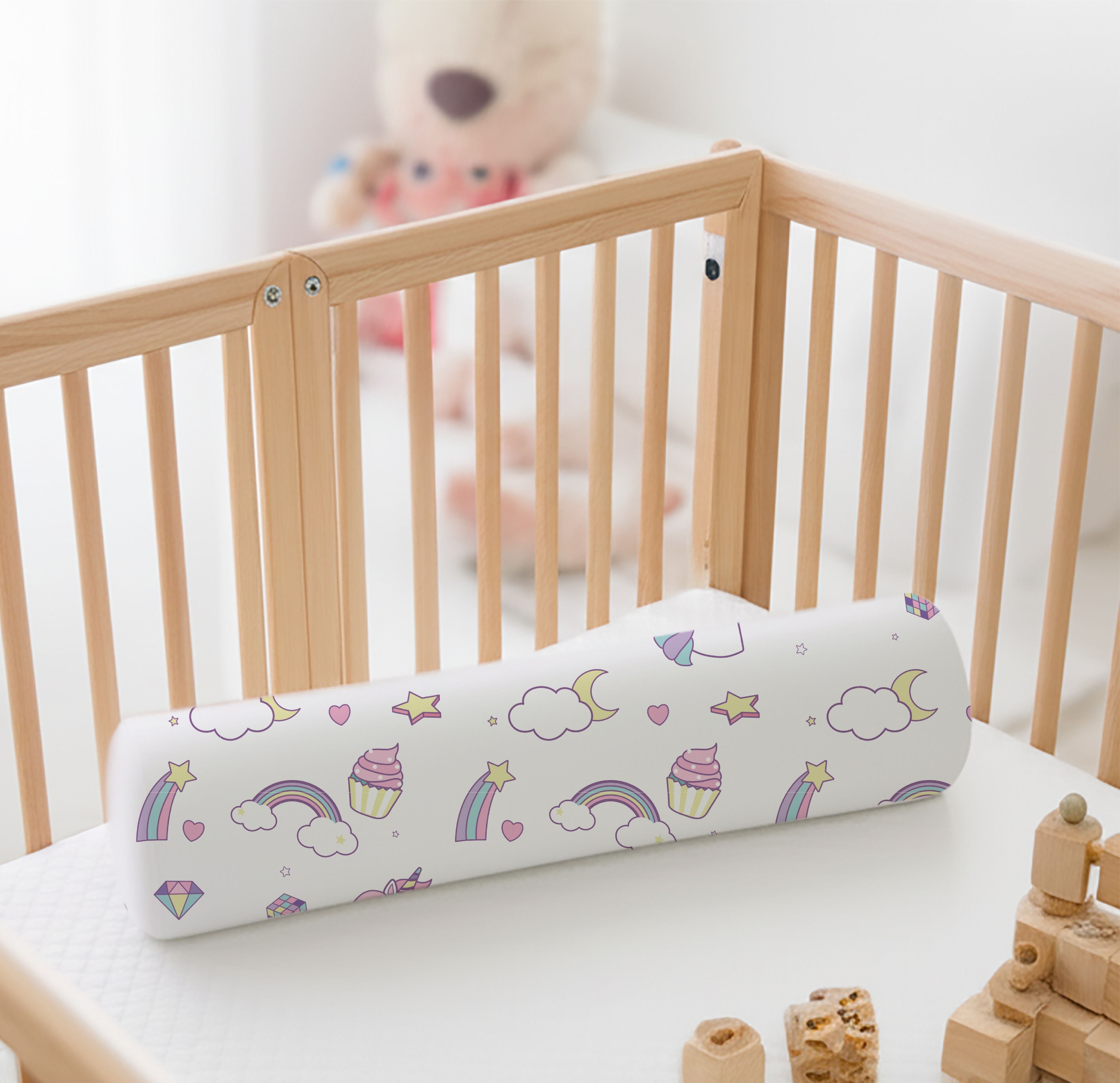 ADMIRAE baby bolster pillow with rainbow and cloud design placed inside wooden crib